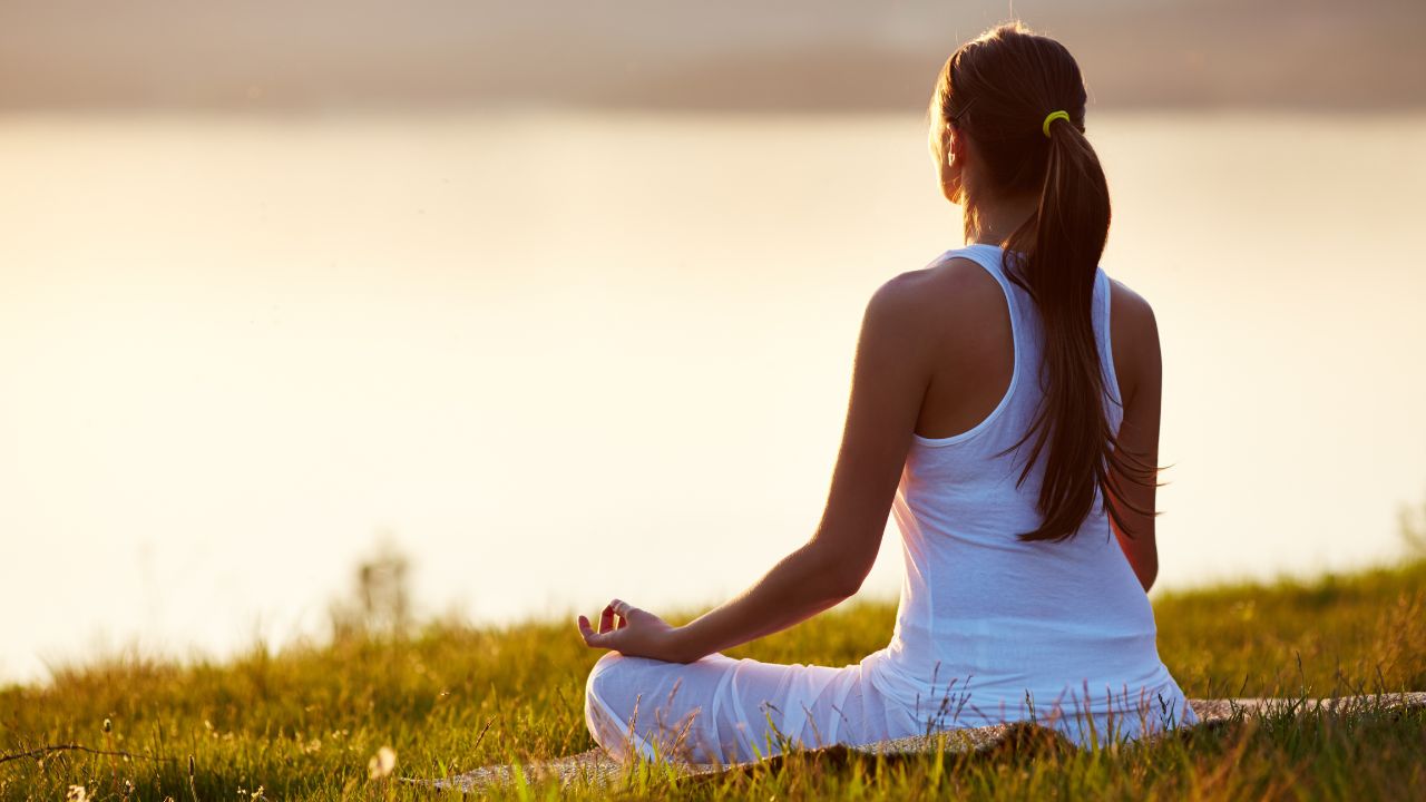 woman meditating toward a lake